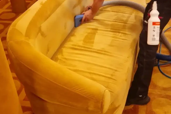 A Prestige technician performing a specialist wet extraction upholstery clean on a luxury sofa at Langan's Brasserie, Mayfair.