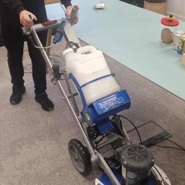 A Prestige technician performing a low-moisture commercial carpet clean within the Canva offices at Hoxton Square.