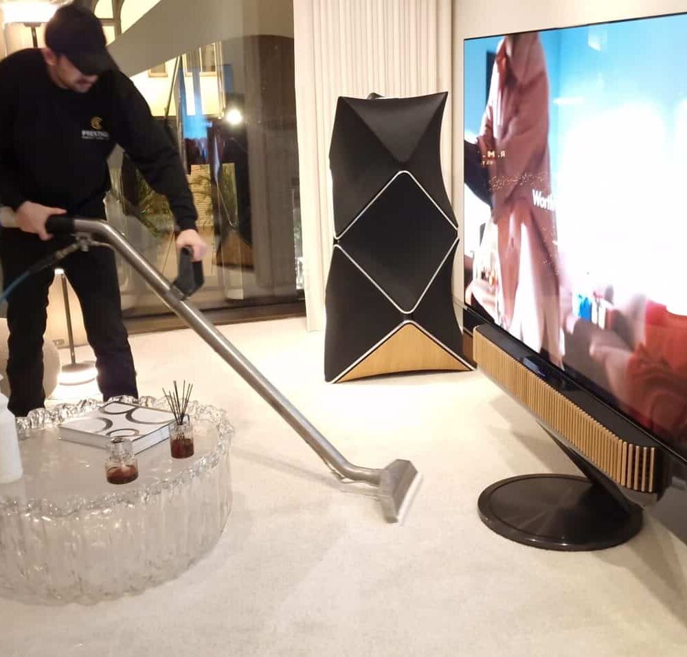 Prestige technician performing precise wet extraction cleaning near high-value audio equipment at Bang & Olufsen London.