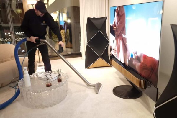 Prestige technician cleaning a luxury rug at the Bang & Olufsen flagship store on New Bond Street, London, working safely around high-end audio-visual equipment.